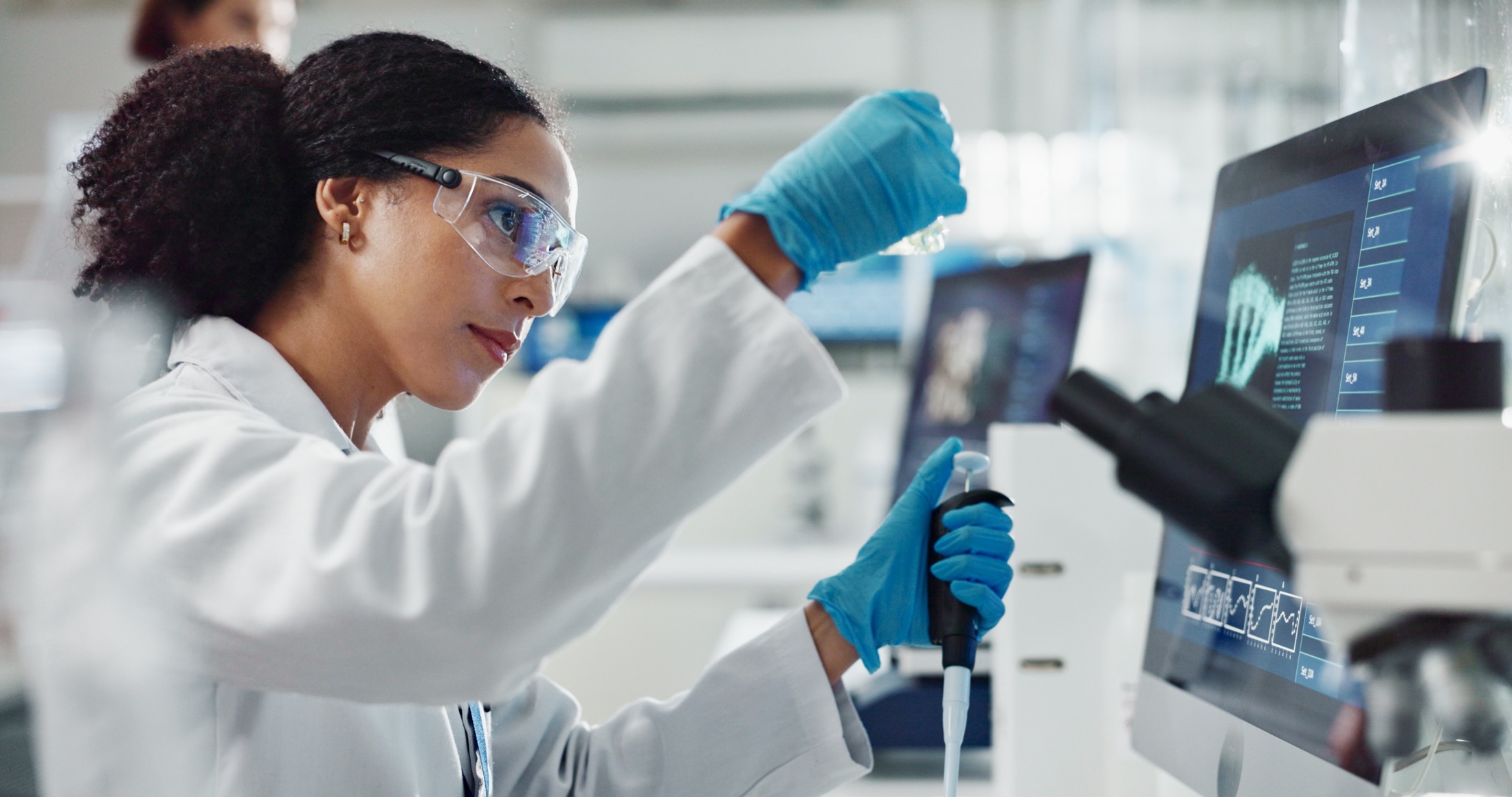 A laboratory scientist analyzing a biological sample with digital tools
